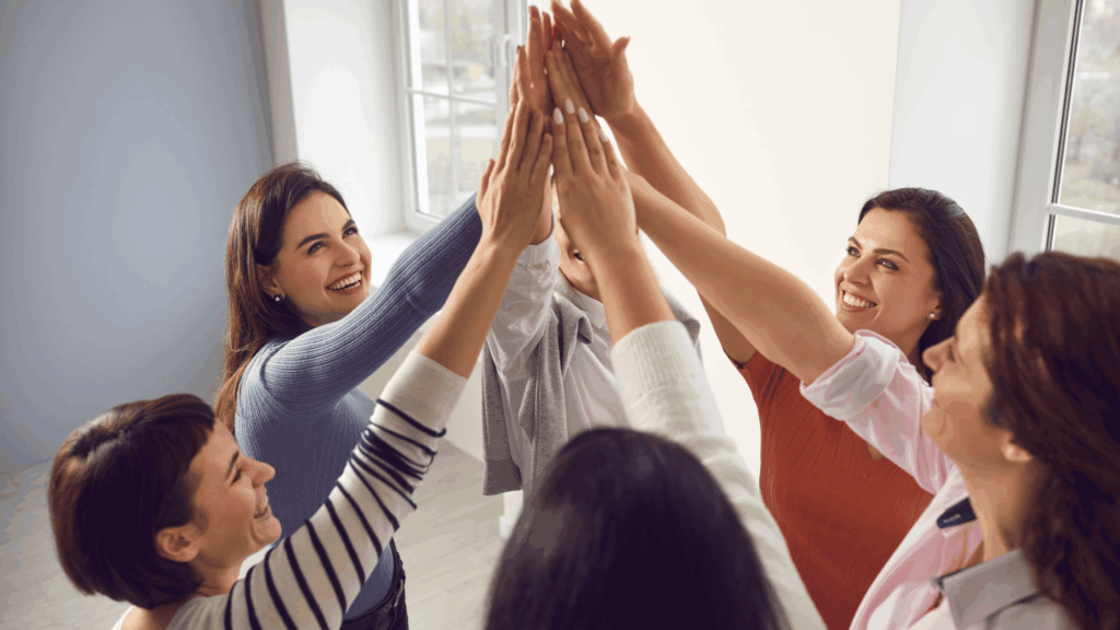 6 female identifying individuals standing in a circle giving eachother a high five