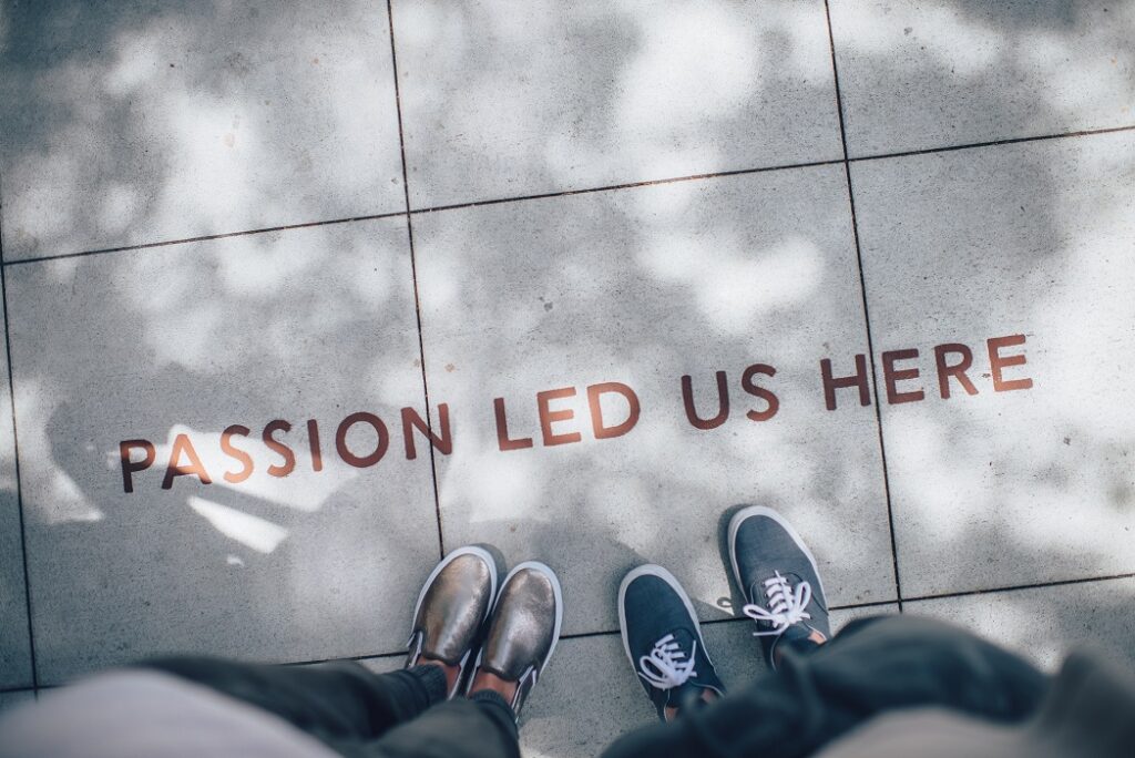 A vview of a sidewalk with the words "passion led us here" written in red on the sidewalk
