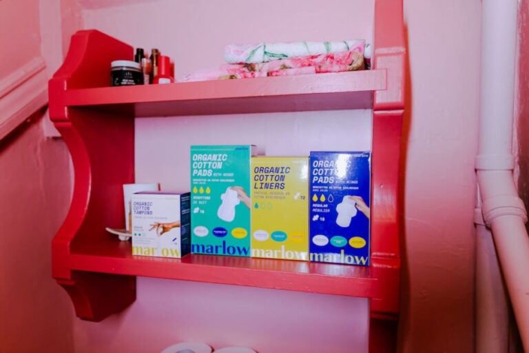 A shelf on a wall holding organic cotton pads, liners and tampons by Marlow