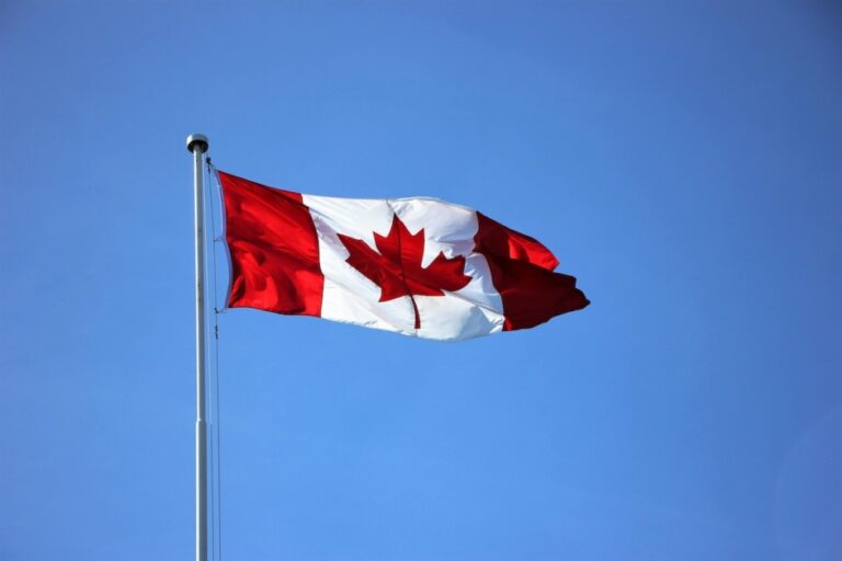 The Canadian flag flying in the wind on a clear sunny day